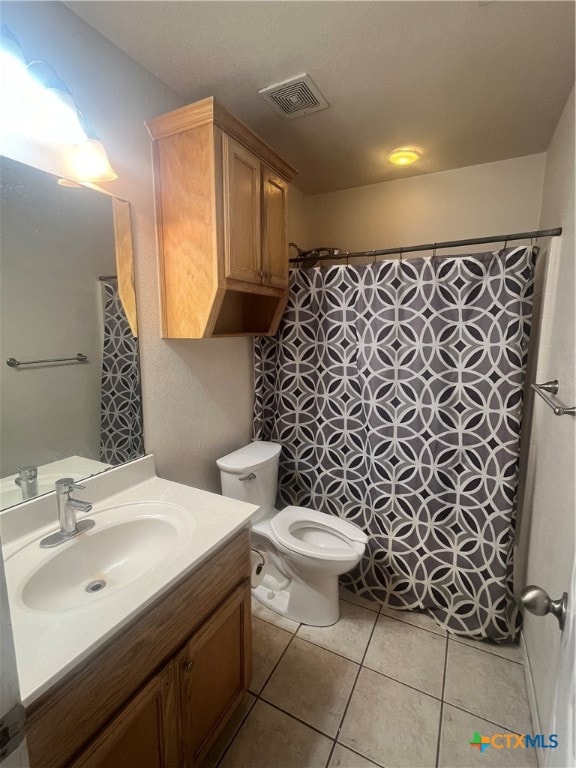 bathroom featuring toilet, walk in shower, vanity, and tile patterned floors