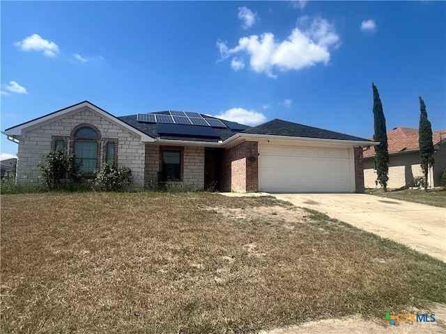 view of front of house with a garage, a front lawn, and solar panels