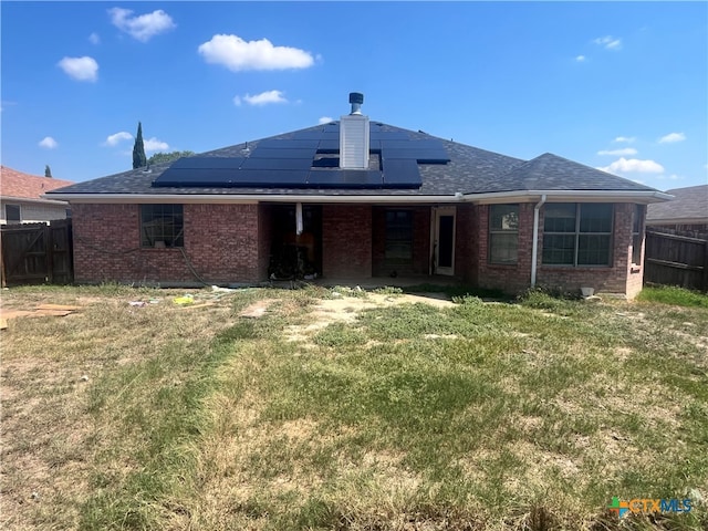 back of property featuring solar panels and a yard