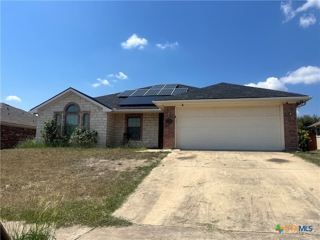 ranch-style home featuring a garage and solar panels