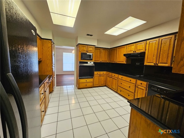 kitchen featuring black appliances, decorative backsplash, light tile patterned flooring, and sink