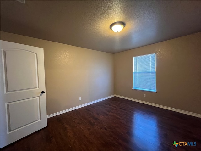 empty room featuring dark hardwood / wood-style flooring and a textured ceiling