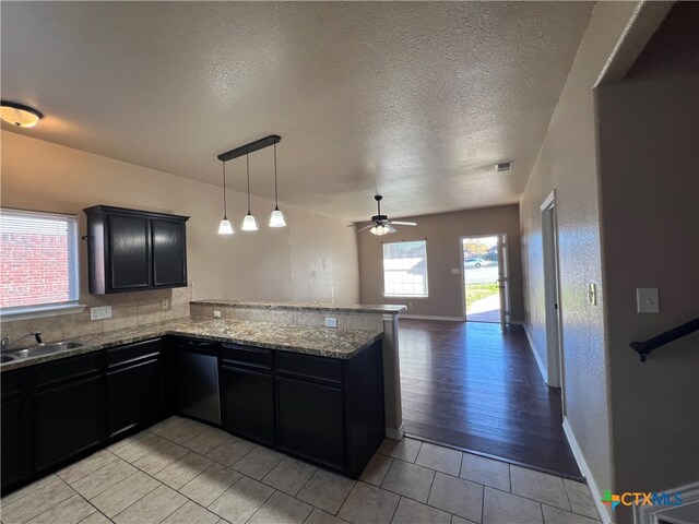 kitchen with a textured ceiling, sink, light hardwood / wood-style floors, dishwasher, and kitchen peninsula