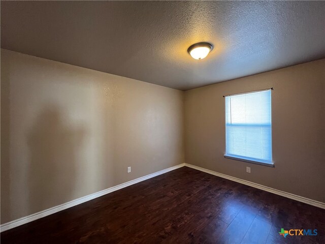 unfurnished room with a textured ceiling and dark hardwood / wood-style flooring