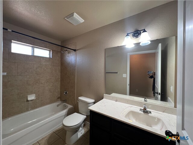 full bathroom with tile patterned floors, toilet, tiled shower / bath, a textured ceiling, and vanity