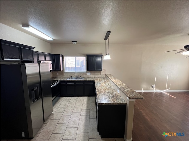 kitchen with stainless steel refrigerator with ice dispenser, kitchen peninsula, a textured ceiling, light hardwood / wood-style flooring, and decorative light fixtures