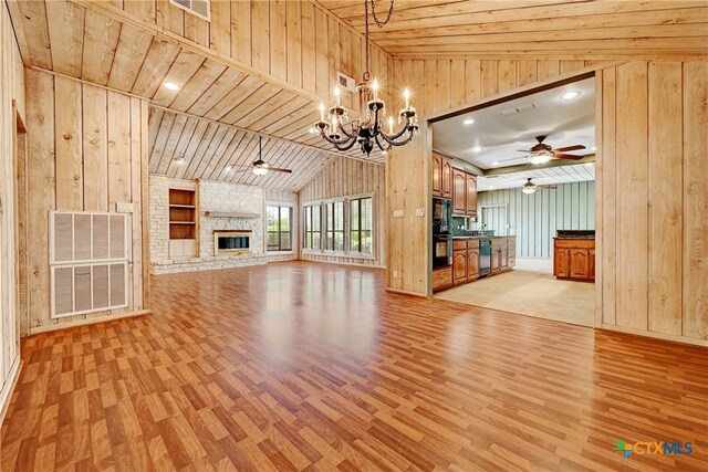 210 Oak Creek Cir, Luling, TX 78648 - unfurnished living room with ceiling fan, light wood-style flooring, wood walls, a chandelier, and lofted ceiling
