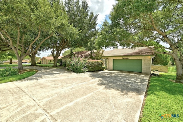210 Oak Creek Cir, Luling, TX 78648 - obstructed view of property featuring driveway, brick siding, an attached garage, and a tiled roof