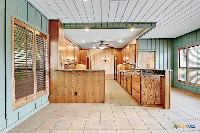210 Oak Creek Cir, Luling, TX 78648 - kitchen featuring a peninsula, wooden walls, light tile patterned floors, ceiling fan, and dark stone counters