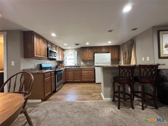 502 N Cherry St, Seguin, TX 78155 - kitchen featuring stainless steel appliances, a sink, light carpet, a breakfast bar area, and recessed lighting