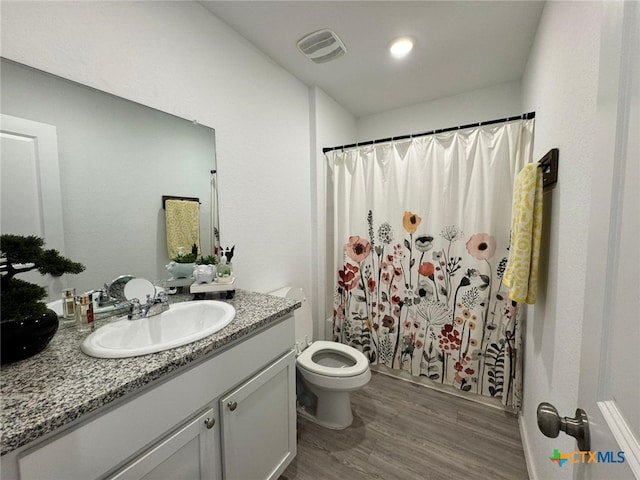 full bathroom featuring hardwood / wood-style flooring, vanity, toilet, and shower / tub combo