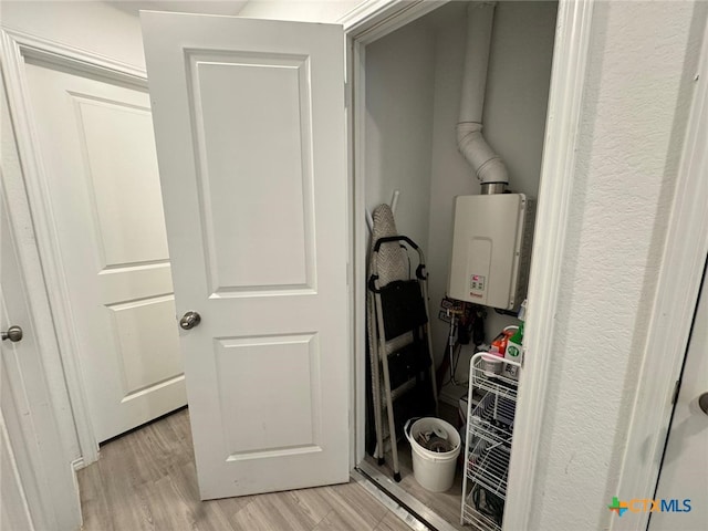 washroom with light hardwood / wood-style floors and water heater