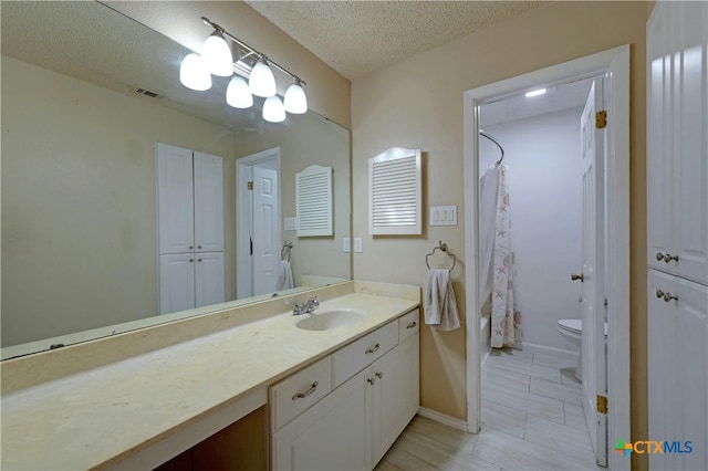 full bathroom with shower / bath combination with curtain, vanity, a textured ceiling, and toilet