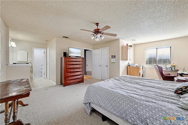 bedroom featuring a textured ceiling, light colored carpet, ceiling fan, and connected bathroom