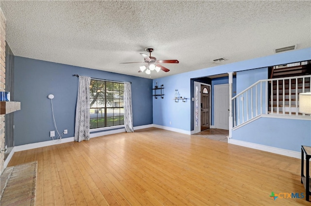 unfurnished living room with a fireplace, light hardwood / wood-style floors, a textured ceiling, and ceiling fan