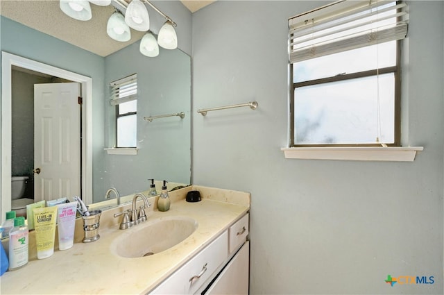 bathroom featuring vanity, a textured ceiling, and toilet