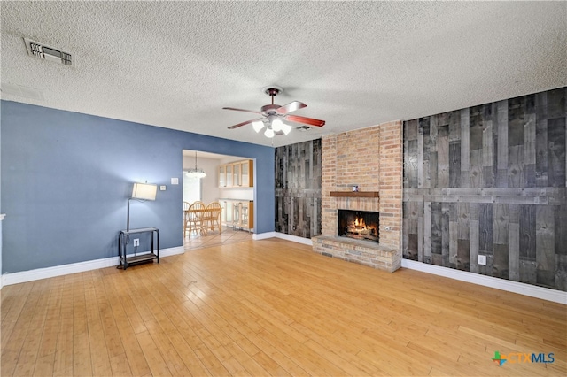 unfurnished living room with hardwood / wood-style floors, ceiling fan, a textured ceiling, and a fireplace