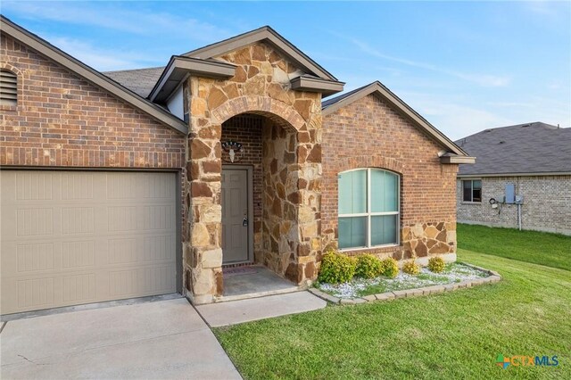 206 Danielle Dr, Killeen, TX 76542 - view of front of house featuring stone siding, concrete driveway, a front lawn, an attached garage, and brick siding