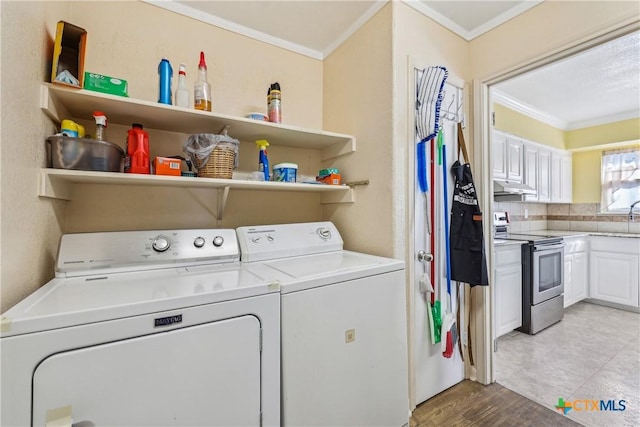 laundry area with light wood-style flooring, laundry area, crown molding, and washer and clothes dryer