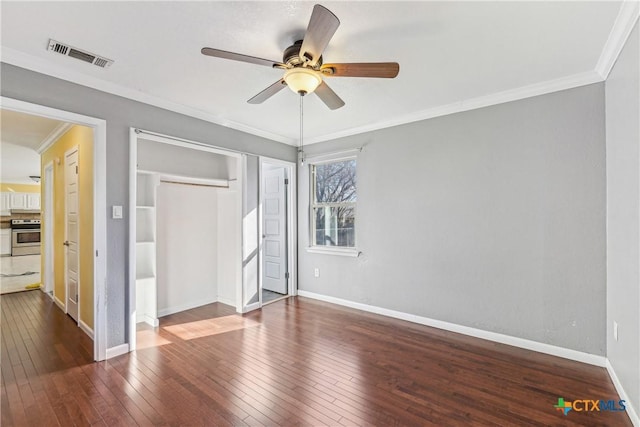 unfurnished bedroom featuring a closet, visible vents, ornamental molding, baseboards, and hardwood / wood-style flooring