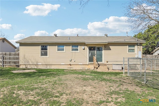 back of property with entry steps, a yard, and fence