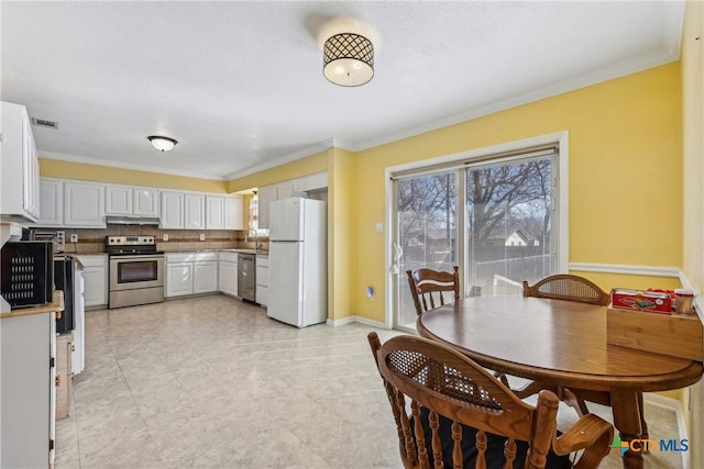 kitchen featuring under cabinet range hood, stainless steel appliances, a sink, ornamental molding, and tasteful backsplash