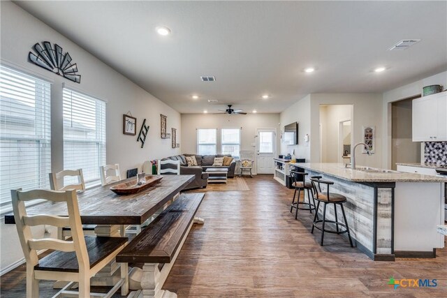 dining space featuring ceiling fan, sink, and hardwood / wood-style flooring