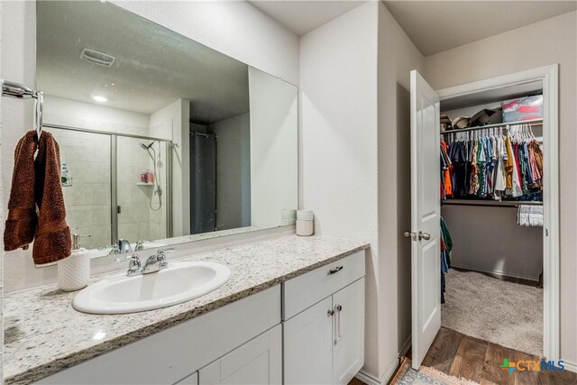 bathroom featuring hardwood / wood-style floors, vanity, and a shower with shower door