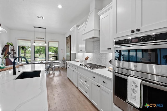 1306 Crystal Spgs, Salado, TX 76571 - kitchen featuring stainless steel appliances, a sink, decorative backsplash, white cabinets, and custom exhaust hood