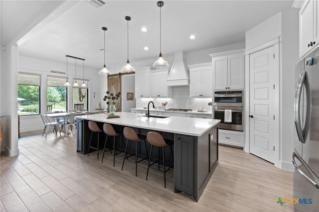 1306 Crystal Spgs, Salado, TX 76571 - kitchen with appliances with stainless steel finishes, a sink, custom range hood, a breakfast bar area, and white cabinets