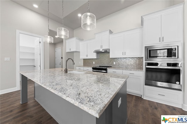 kitchen featuring white cabinets, hanging light fixtures, sink, an island with sink, and appliances with stainless steel finishes