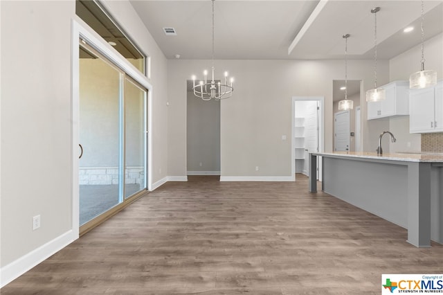 unfurnished dining area featuring sink, light hardwood / wood-style flooring, and a notable chandelier