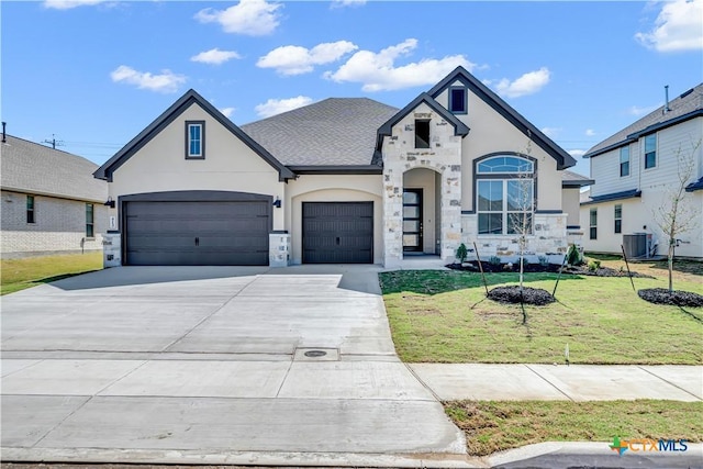 french country home featuring central AC, stucco siding, concrete driveway, a front lawn, and stone siding