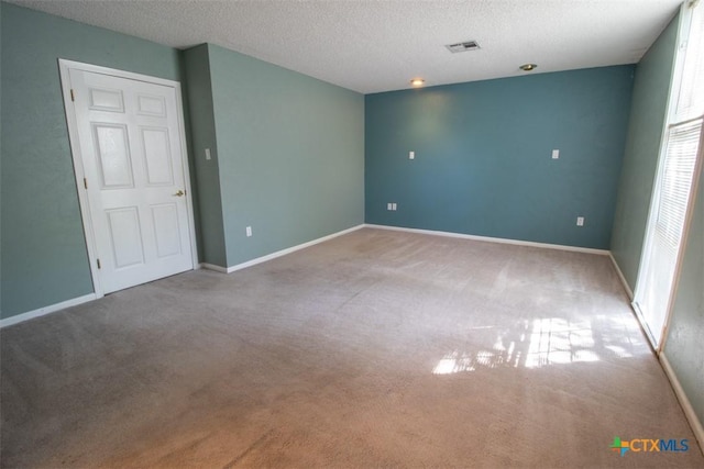 empty room with carpet floors, a textured ceiling, and baseboards