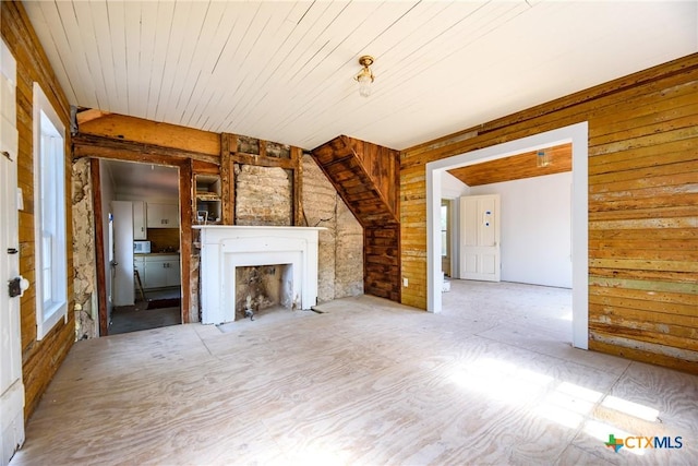 unfurnished living room featuring a fireplace and wood walls