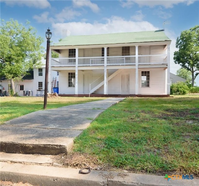 view of front of house featuring a balcony and a front lawn