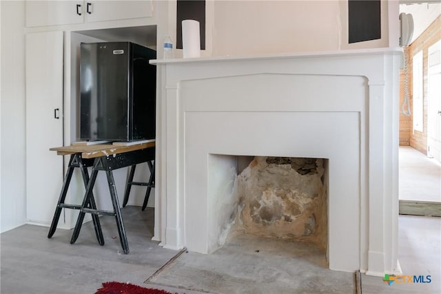 room details with black refrigerator and concrete flooring