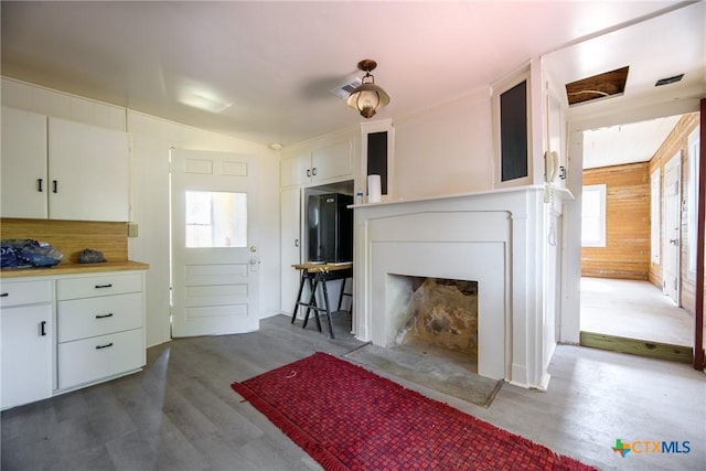 interior space featuring wood walls, vaulted ceiling, hardwood / wood-style flooring, a fireplace, and white cabinetry