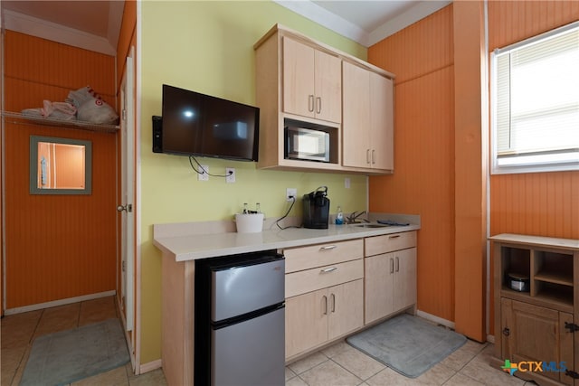 kitchen featuring wood walls, crown molding, light brown cabinetry, light tile patterned flooring, and stainless steel refrigerator