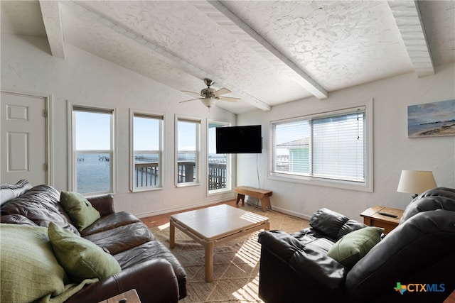 living room featuring vaulted ceiling with beams, ceiling fan, and a textured ceiling