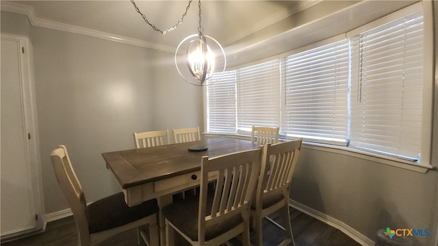 dining space featuring dark wood-type flooring, an inviting chandelier, and crown molding