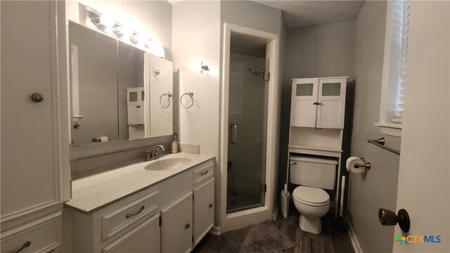 bathroom with hardwood / wood-style flooring, a shower with door, a textured ceiling, vanity, and toilet