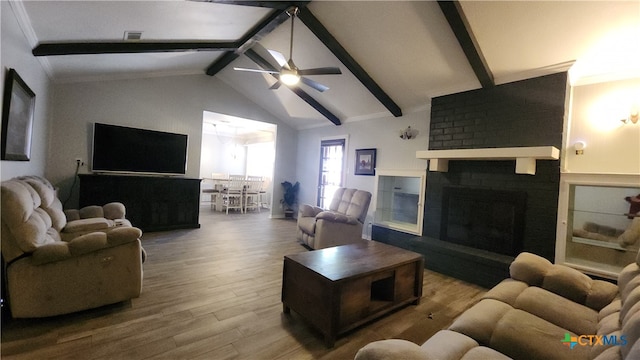 living room with lofted ceiling with beams, crown molding, a fireplace, hardwood / wood-style flooring, and ceiling fan