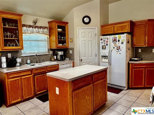 kitchen featuring sink, light tile patterned floors, a kitchen island, backsplash, and white appliances