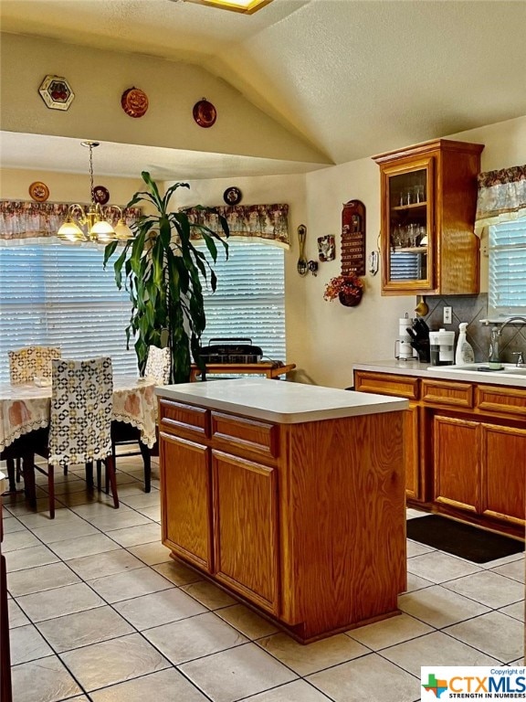 kitchen featuring sink, a chandelier, a center island, pendant lighting, and vaulted ceiling