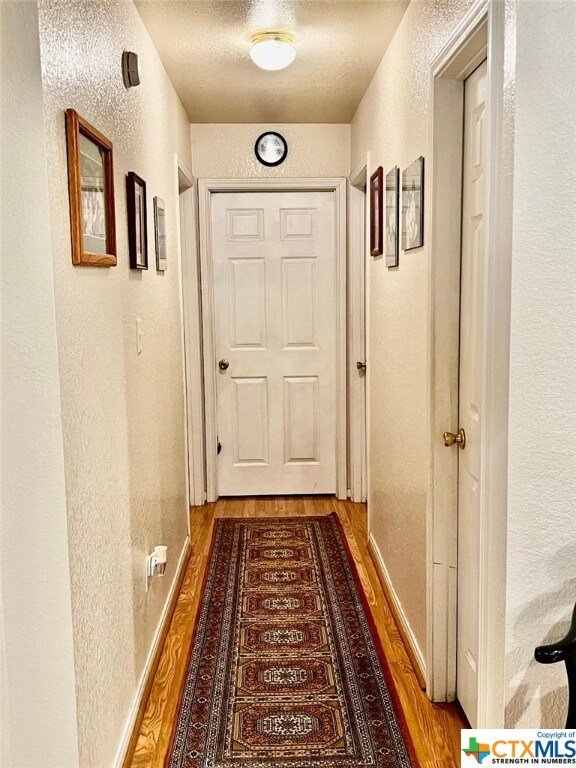 4305 Foster Ln, Killeen, TX 76549 - hallway featuring a textured wall, wood finished floors, and a textured ceiling