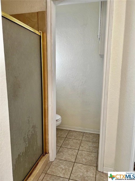 bathroom featuring walk in shower, toilet, and tile patterned flooring