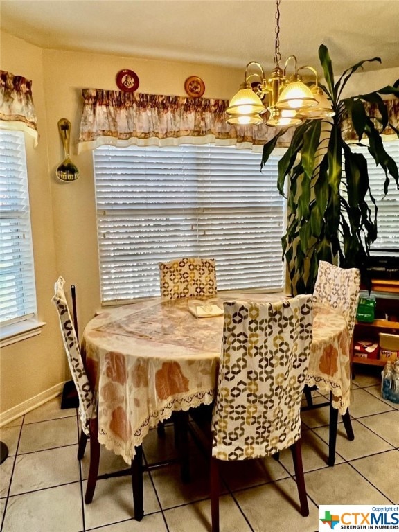 tiled dining room with an inviting chandelier