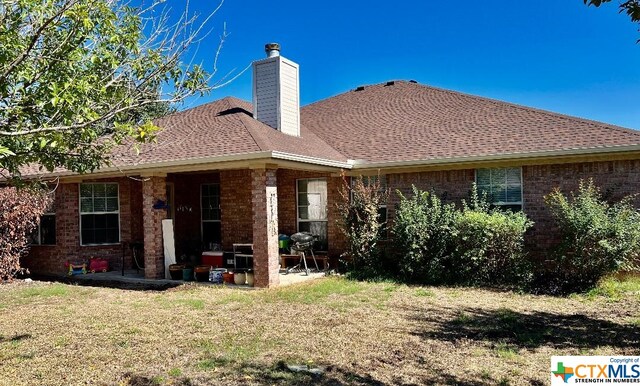 4305 Foster Ln, Killeen, TX 76549 - back of house featuring a chimney, a lawn, and brick siding