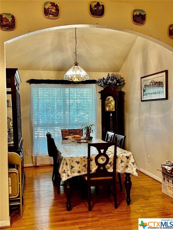 4305 Foster Ln, Killeen, TX 76549 - dining space featuring wood finished floors, arched walkways, vaulted ceiling, and baseboards